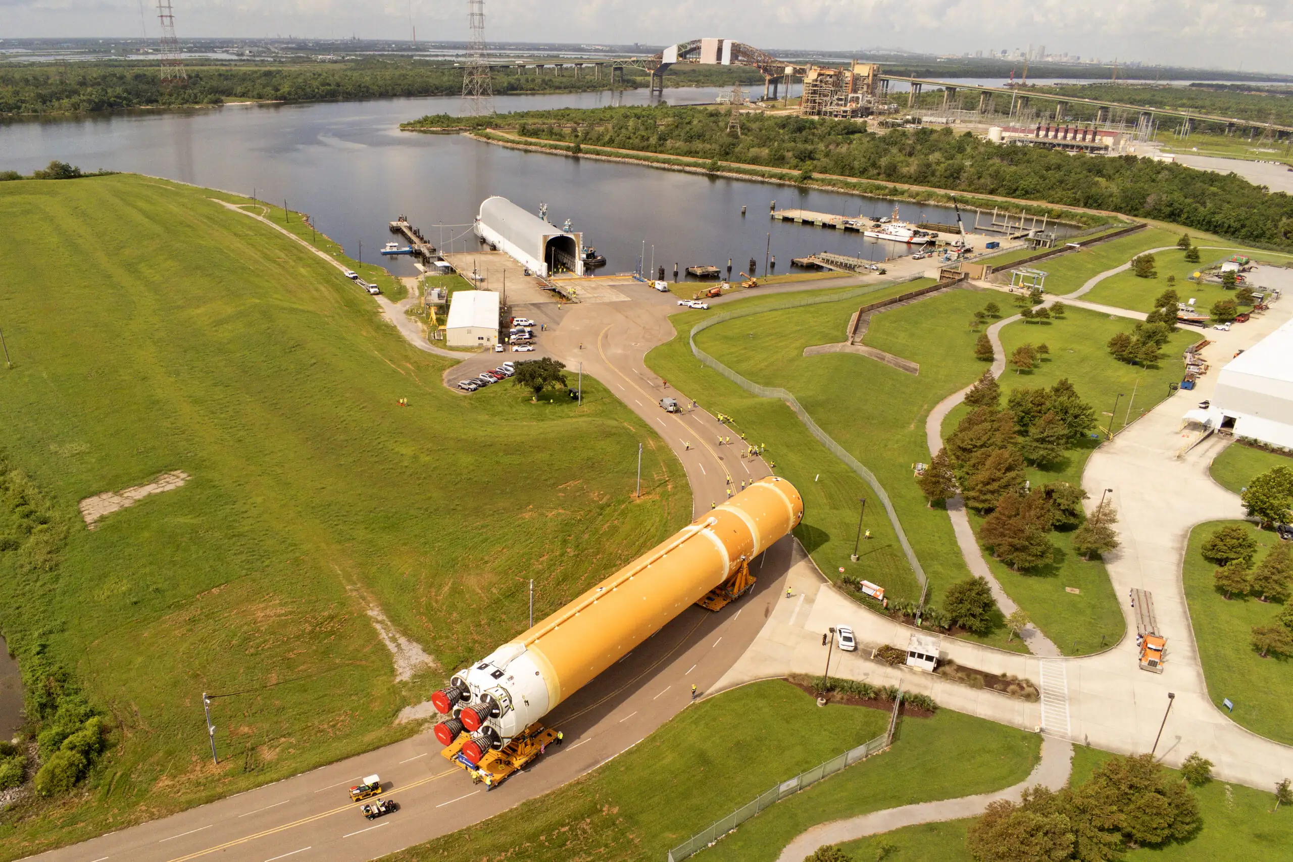 Transfert de l'immense étage principal orange de la fusée SLS pour la mission Artemis II au centre d'assemblage de Michoud.